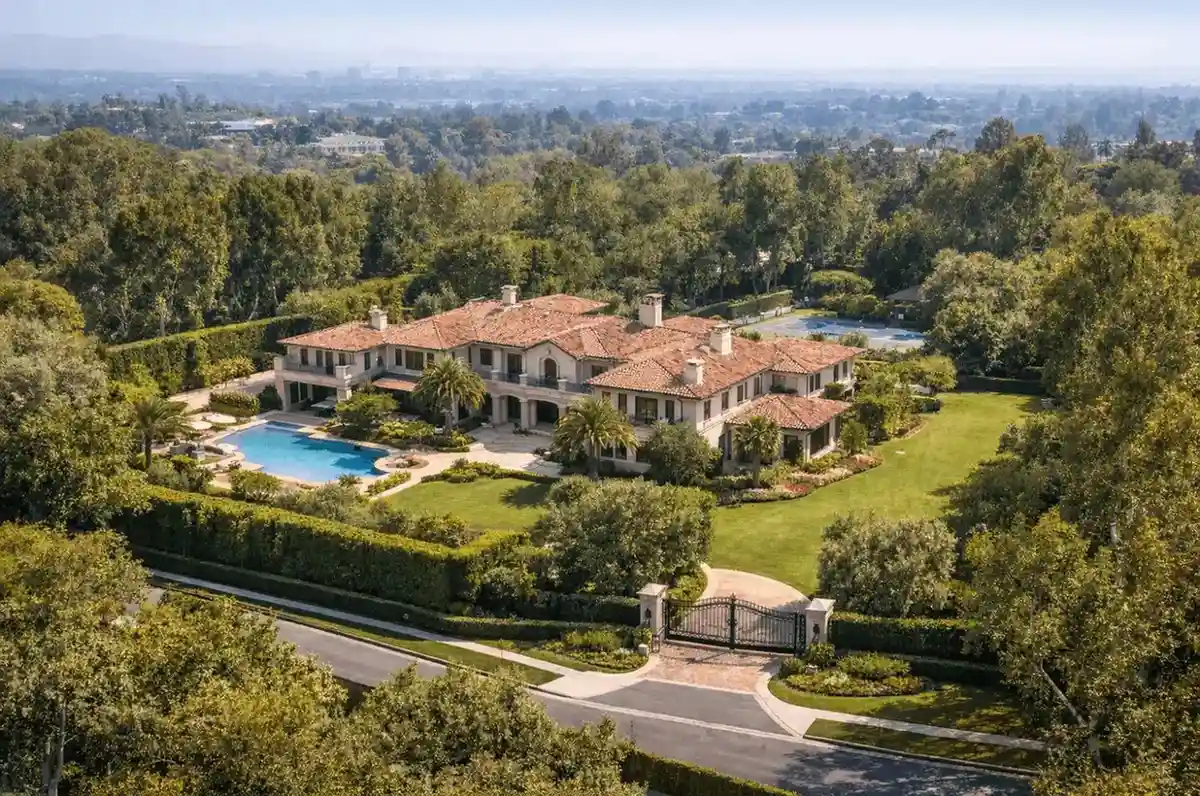 Aerial view of luxury gated estate with pool, palm trees, and expansive grounds
