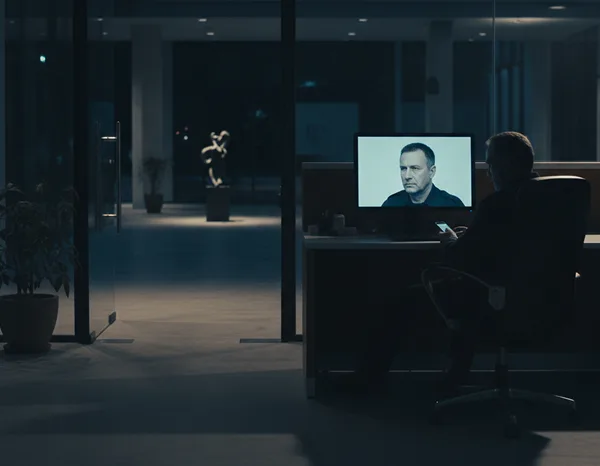 Night security guard at an office desk monitoring CCTV in a modern building