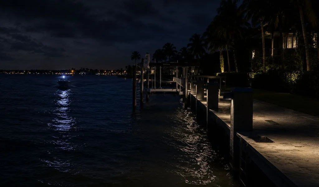 A small craft approaching a Naples private dock at night illustrating waterborne security risk